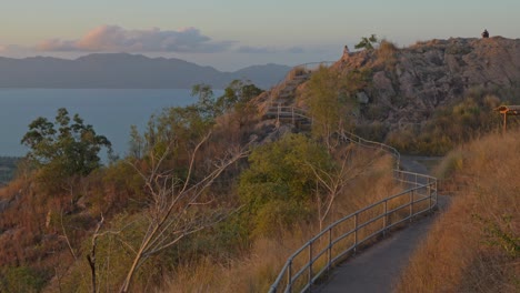 travelers walk on stair pathway of castle hill lookout with magnetic island in horizon