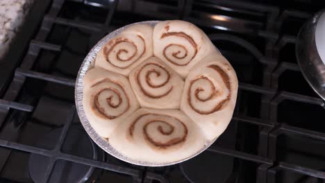 rollos de canela crudos en una sartén sobre la estufa que se elevan antes de hornear - girando para aumentar uniformemente en un lapso de tiempo