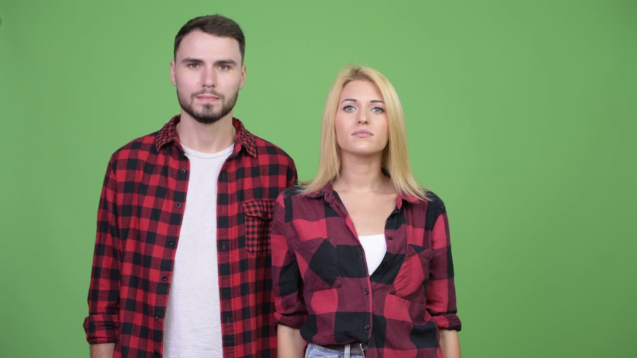 Young couple pointing to camera together