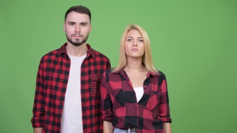 young couple pointing to camera together