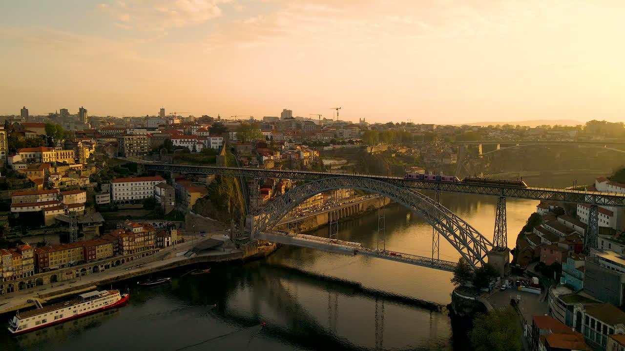 황금빛 일출 동안 다리와 역사적인 도시 포르토에서 기차의 공중 드론 샷