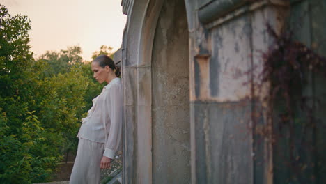 lady relaxing ancient architecture leaning on old wall. woman standing terrace