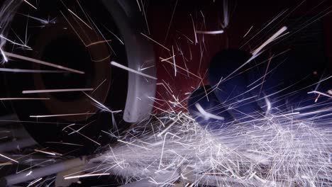 closeup in workshop: sparks fly from cutting disc cutting steel rack