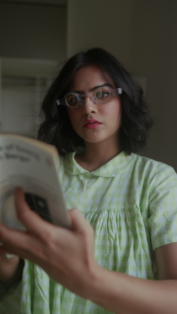 Young woman in soft green dress reading book indoors, focused and calm mood