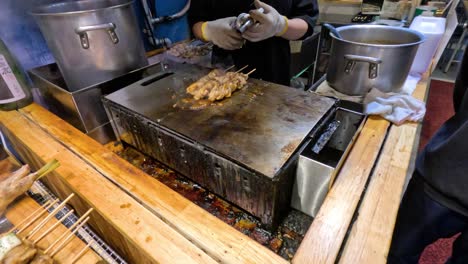 cooking meat skewers on a hot griddle outdoors