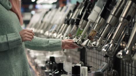 woman chooses a blender stick by viewing in the appliances store