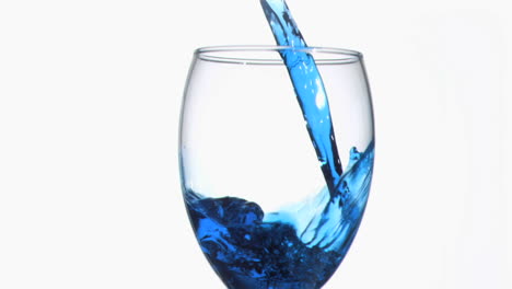 goteo azul en cámara súper lenta fluyendo en un vaso de vino