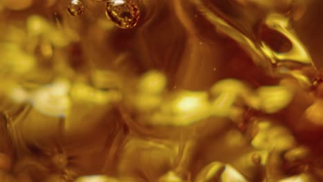 a glass is slowly filling with ambar liquid in slowmotion and macro