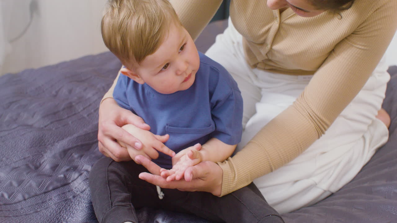 mujer joven abrazando a su lindo bebé mientras se sienta en la cama en casa