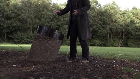 Woman-putting-rubbish-in-park-bin-wide-shot