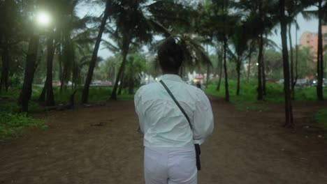 person walking through a palm tree forest during twilight