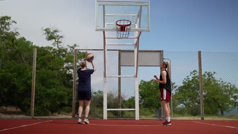 two women playing basketball outdoors