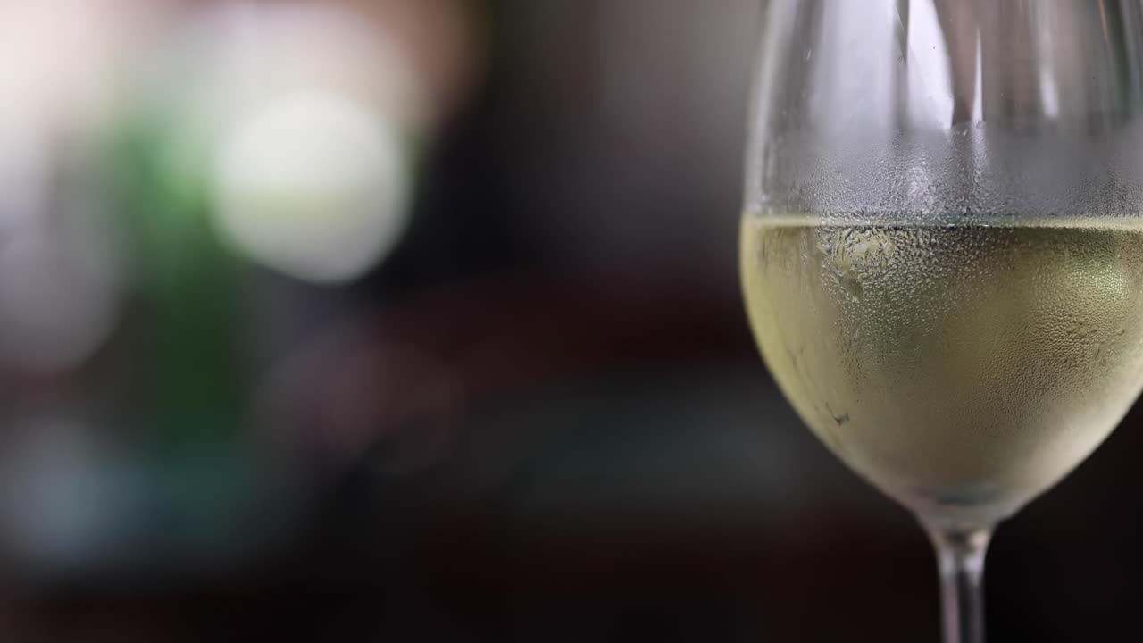 Una vista dettagliata di un calice di vino ghiacciato con uno sfondo sfocato, che evidenzia la condensa e la trasparenza.