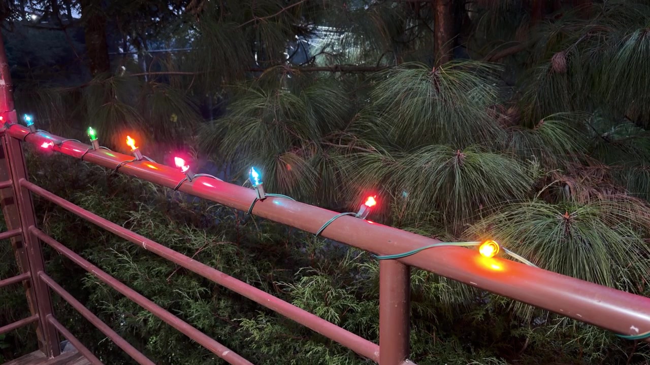 Luces navideñas retro de colores parpadeando en la barandilla de una cabaña por la noche.