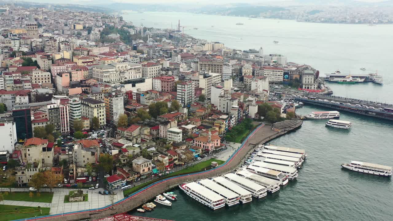 Wide aerial view of Taksim and Karakoy in Istanbul Turkey with ferry boats docked on the coast of the Bosphorus River on a cloudy morning surrounded by old European buildings