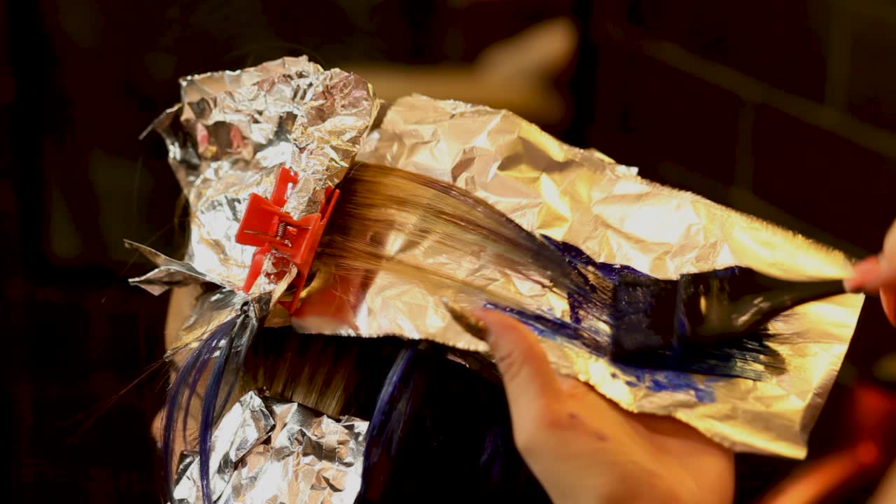 esteticista aplica tinte de pelo púrpura a la punta de la