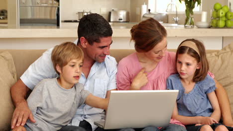 happy family sitting on the sofa using laptop
