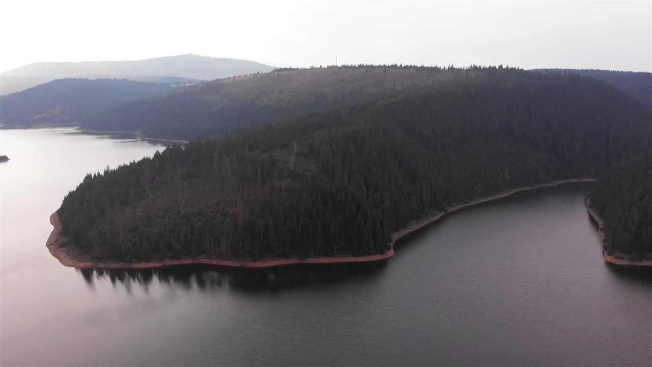 Aerial Footage of Large Lake and mountains surrounded by Pine Forest trees