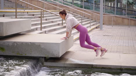 woman doing jumping jacks workout on stairs near a fountain