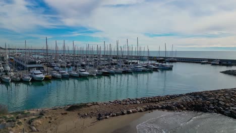 Sailboats-docked-at-the-Coast-and-Port-of-Ginesta-in-Barcelona-on-a-partly-cloudy-day