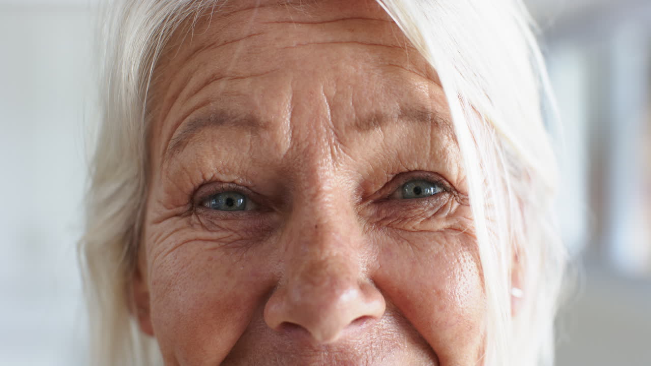 ojos de una mujer caucásica feliz de edad avanzada de pie y riendo en una habitación soleada en casa, cámara lenta