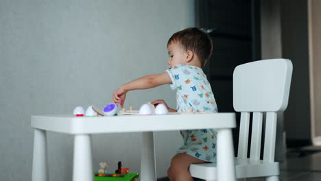 little caucasian boy sitting at the desk in his room. sweet kid peacefully playing with puzzles.