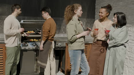 Eine-Nette-Multikulturelle-Gruppe-Von-Freunden,-Die-Sich-Beim-Grillen-Auf-Der-Terrasse-Eines-Hauses-Fröhlich-Unterhalten