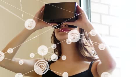 Animation-of-network-of-connections-with-icons-over-woman-wearing-vr-headset