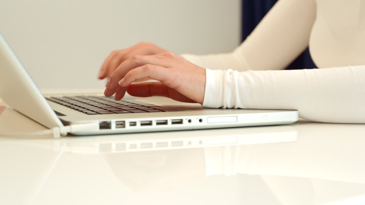 Woman wearing white clothes working on notebook at home, close up