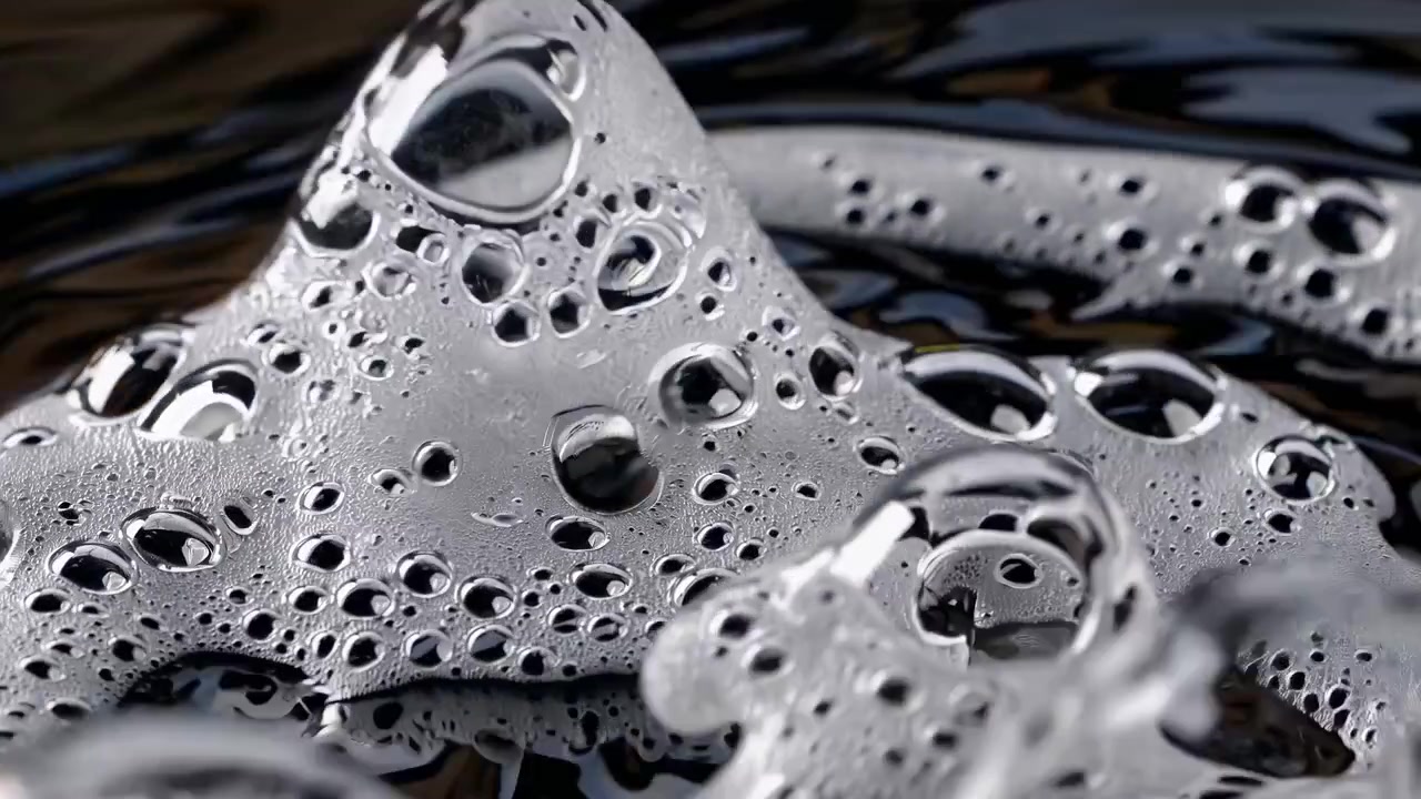Close-up of Bubbles and Foam Dissipating on Dark Liquid Surface