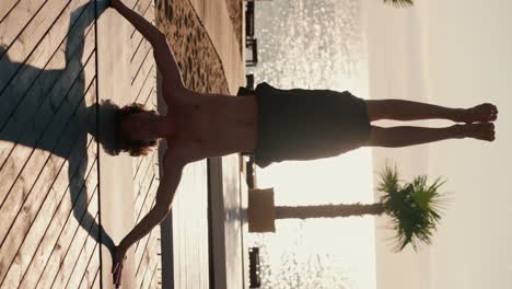 A-brunette-guy-in-black-shorts-stands-on-his-head-during-his-yoga-and-meditation-class-on-a-sunny-beach-in-the-morning