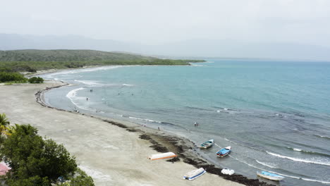 AERIAL---Boats,-people-on-the-beach,-Monte-Rio,-Dominican-Republic,-rising-shot