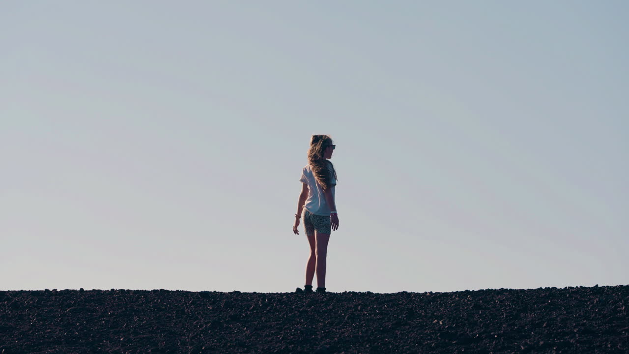 Silhouette of a person standing on a desolate horizon against a clear sky