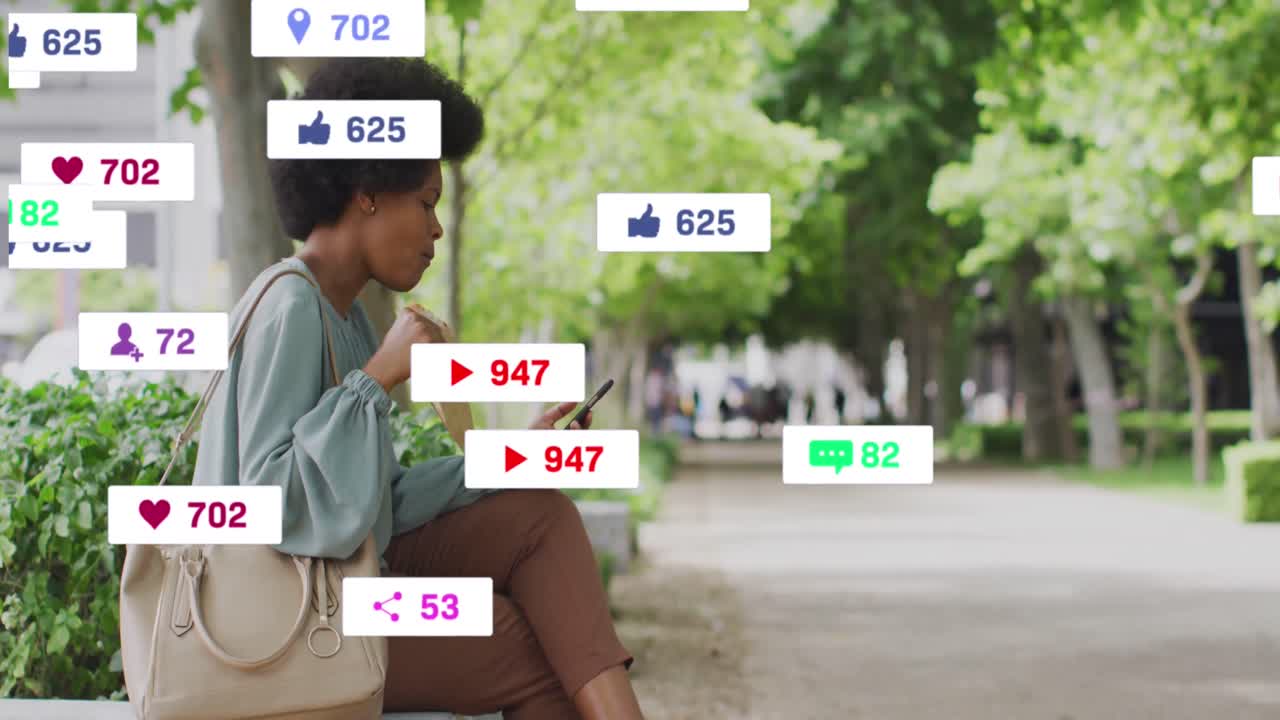 animación de iconos de redes sociales en mujer afroamericana usando teléfono inteligente sentada en el lado de la calle