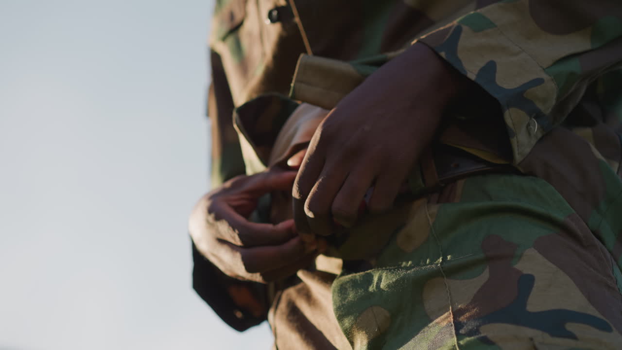 Military Personnel Secures Tactical Equipment, Service Member Fastens Camouflage Gear Carefully, Armed Soldier Meticulously Secures Camouflage Belt As Part Of Field Readiness Preparations