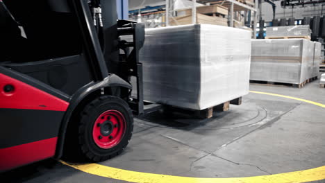 logistics employee drive a forklift containing stacked cargo boxes or packages and slowly pickup box on the floor