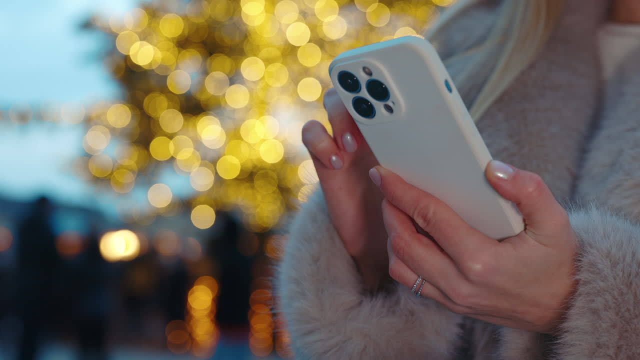 mujer usando el teléfono frente a las luces de navidad
