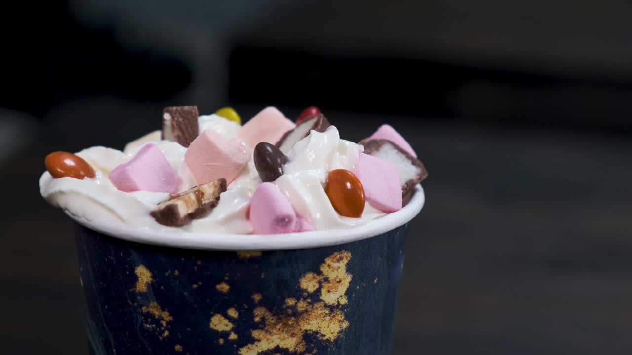 검은색 바탕에 회전하는 테이블에 크림과 마쉬멜로와 함께 클로즈업 달한 디저트.