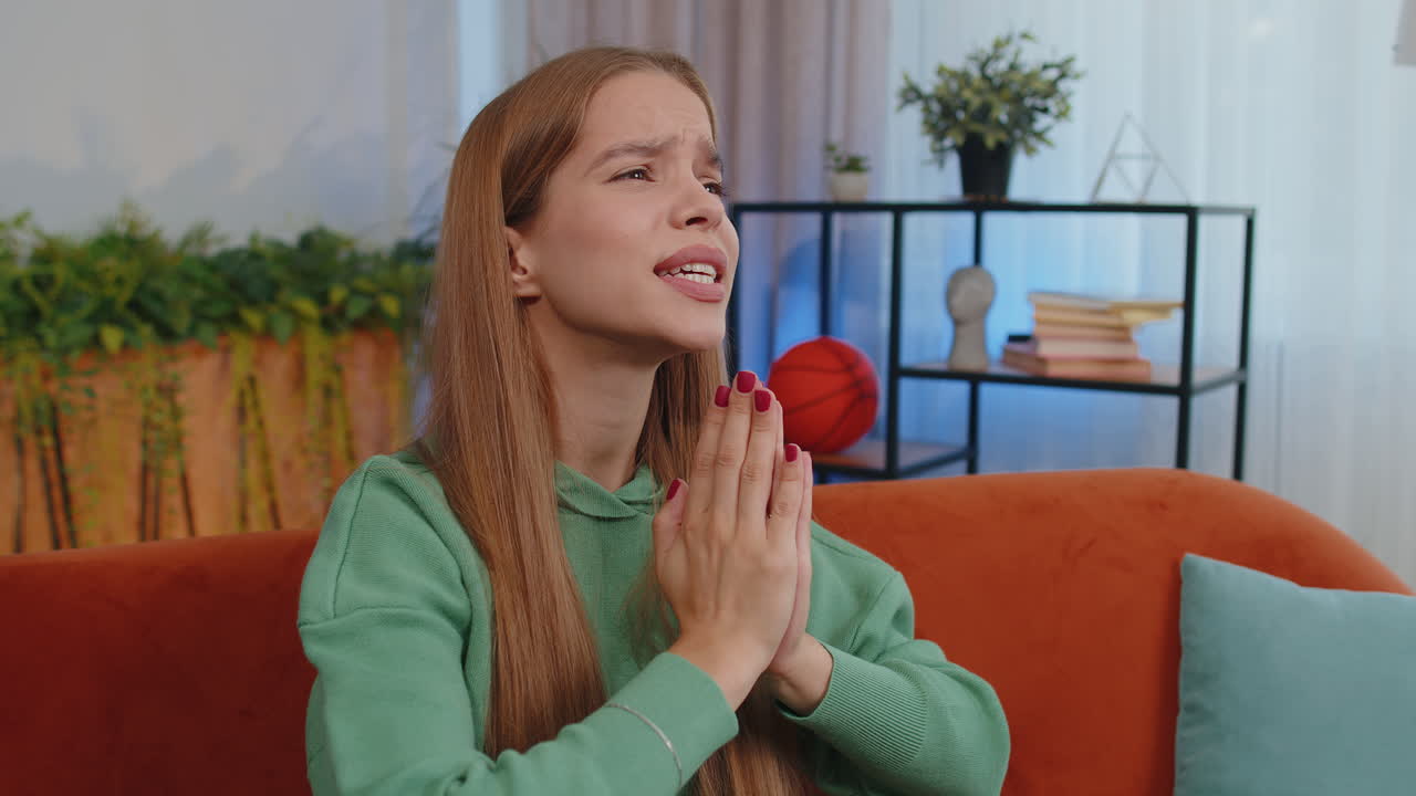 Young girl praying sincerely with folded arms asking God for help, begging apology, making a wish