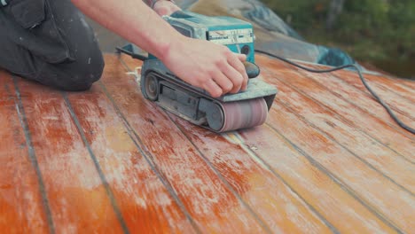 belt sanding roof planking repair rubbing hand over planks