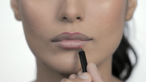 maquillador profesional dando forma a los labios de la mujer con lápiz labial