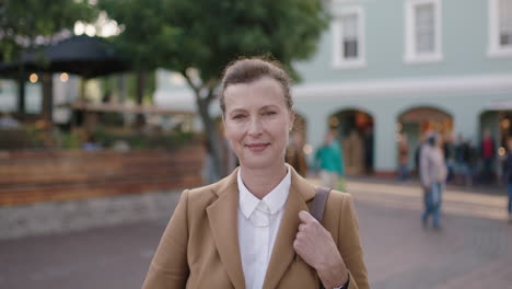 portrait of elegant mature business woman waiting in city smiling confidently looking at camera