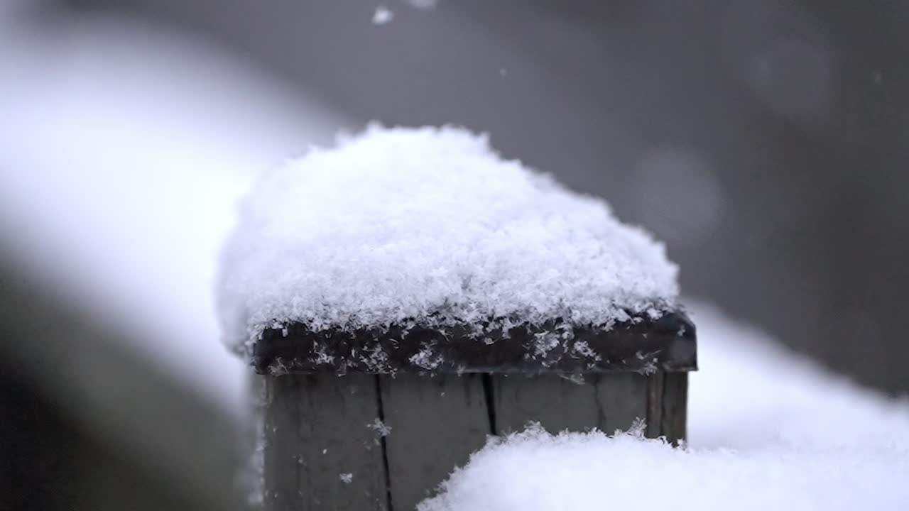 Slow motion background snowfall footage, wooden fence, covered with snow, small snowflakes fall down, copy space, close up