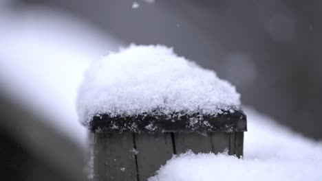 slow motion background snowfall footage, wooden fence, covered with snow, small snowflakes fall down, copy space, close up