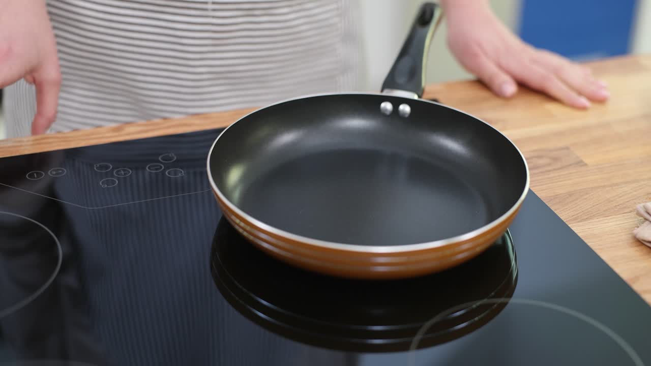 Person preparing to cook on an induction cooktop with a frying pan