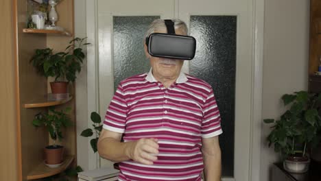 senior grandfather man in virtual headset glasses watching 3d video in 360 vr helmet at home