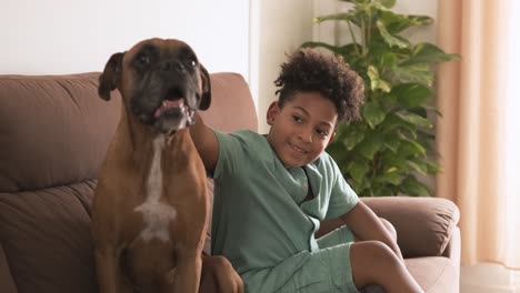 young boy sitting with his boxer dog on a couch