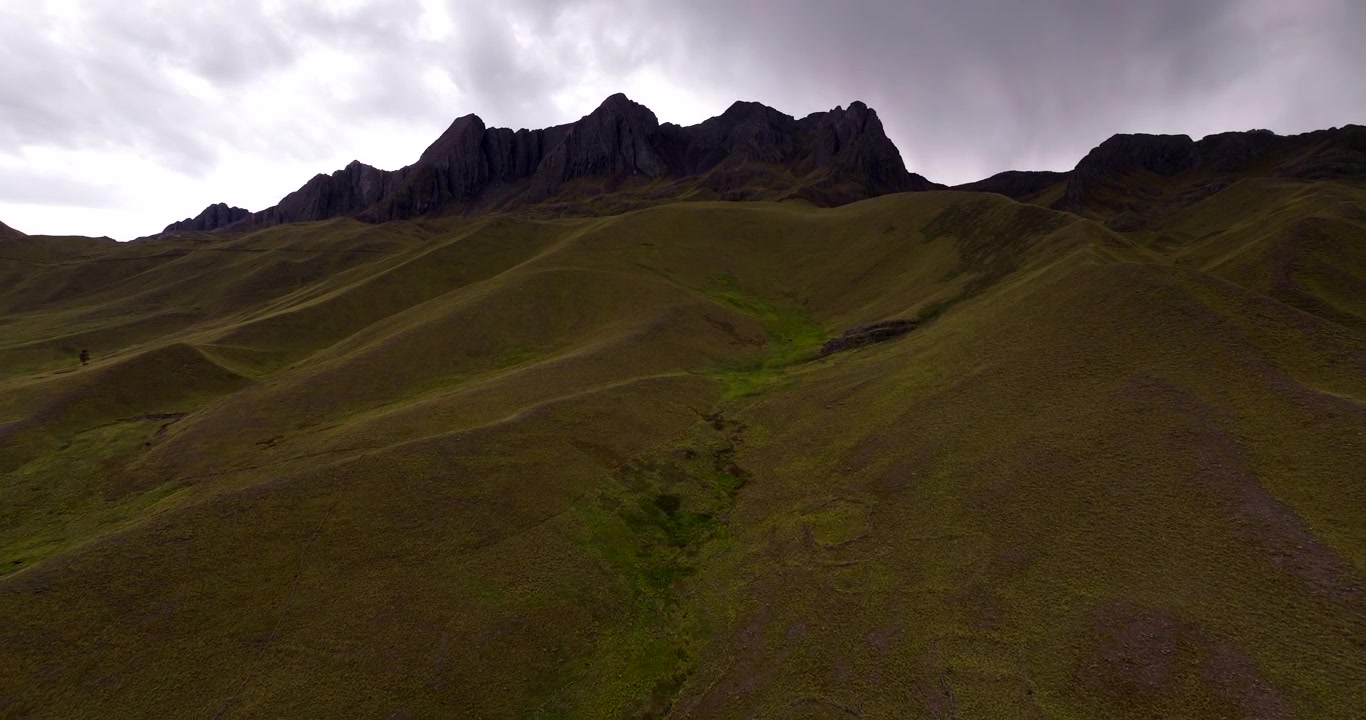 Vista drone di un pendio montano erboso sotto una fitta nuvola nel distretto di Langui, Perù. Avanzamento aereo.