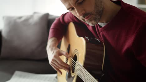Tilt-up-video-of-man-playing-acoustic-guitar-at-home