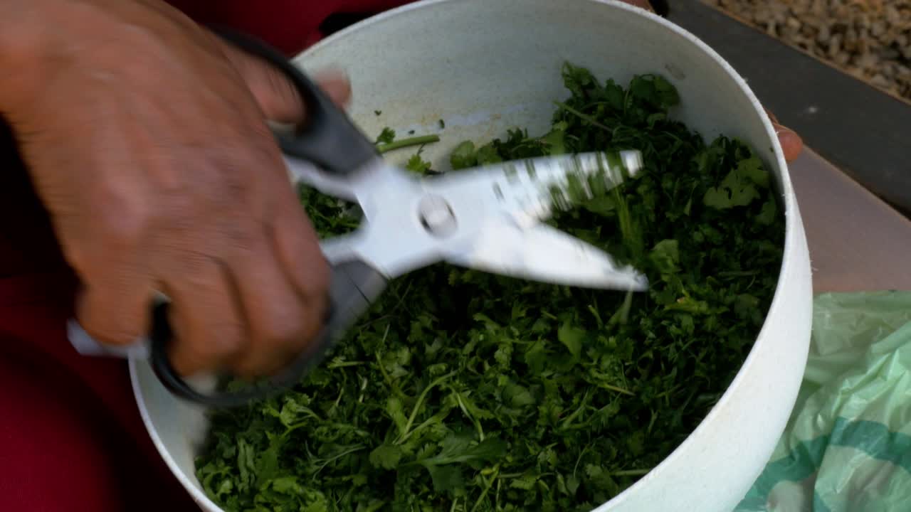 un chef cortando y picando cilantro en un tazón de cerca